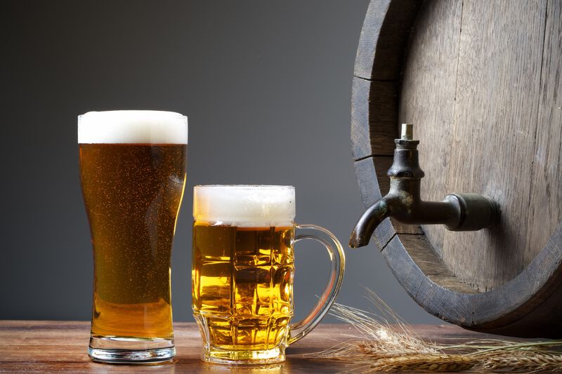 Image of two beer steins with an oak cask and stalks of wheat